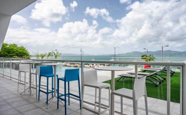 Modern hotel terrace at B&B HOME with bar tables overlooking an infinity pool and the sea
