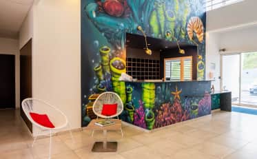 Modern B&B HOME hotel reception area with colorful underwater themed mural and stylish white lounge chairs
