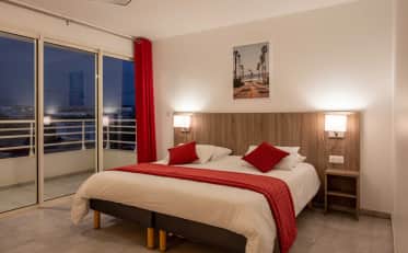 Modern double room at B&B HOME featuring a comfortable bed with red accents and a private balcony with evening views