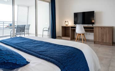 Modern B&B HOME hotel room with king bed and private balcony featuring outdoor seating and sea view