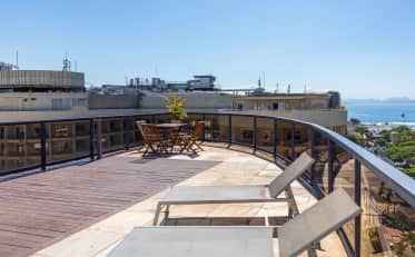 Sunny B&B HOTEL rooftop terrace with sun loungers and dining area overlooking the ocean