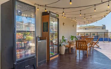 Hotel terrace with wooden deck seating area and a poolside market stocked with drinks and snacks