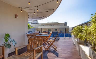Relaxing B&B HOTEL rooftop terrace with wooden furniture and a small pool under string lights