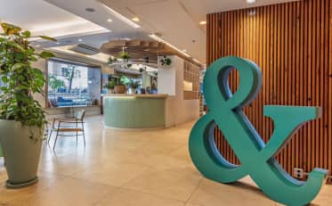 Modern B&B HOTEL lobby with reception desk and stylish decor featuring a large teal ampersand sculpture
