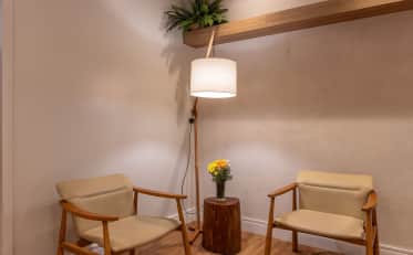 Cozy seating area in a B&B HOTEL lobby with two wooden chairs and a rustic side table featuring fresh flowers