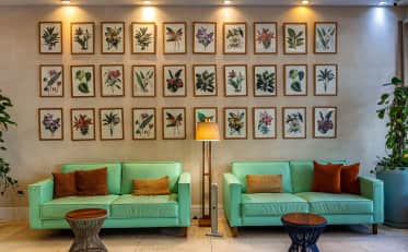 Modern B&B HOTEL lobby lounge area with mint green sofas and botanical art gallery wall