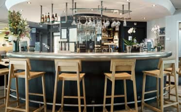 Moderno bar dell'hotel con sgabelli in legno e bancone elegante presso B&B HOME