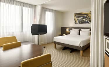 Camera d'albergo moderna presso B&B HOME con letto confortevole e una piccola zona pranzo con sedie gialle