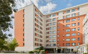 Moderna facciata esterna dell'hotel B&B HOME con pareti arancioni e bianche e alberi verdi