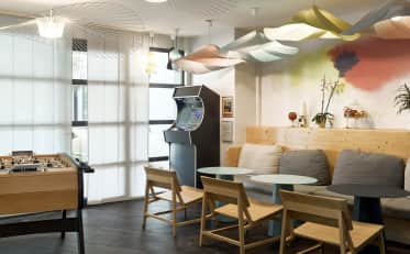 Moderna lounge dell'hotel B&B HOME con biliardino videogioco arcade e accogliente area salotto con lampade di design