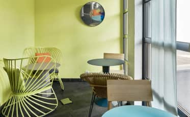 Moderna area lounge presso l'hotel B&B HOME con sedute colorate e pareti giallo brillante