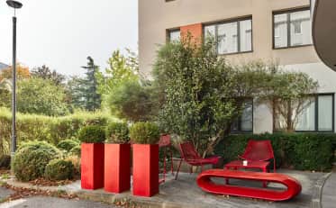 Moderna terrazza esterna con mobili rossi e vegetazione lussureggiante presso l'hotel B&B HOME
