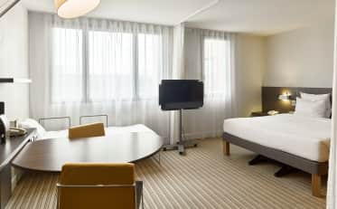 Moderna camera familiare presso l'hotel B&B HOME con letto matrimoniale e zona pranzo separata con sedie