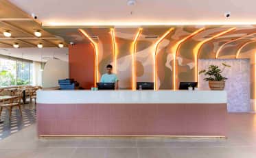 Reception desk at B&B HOTEL featuring modern design with warm LED lighting and a friendly staff member
