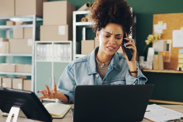 Frustrated woman at laptop on phone