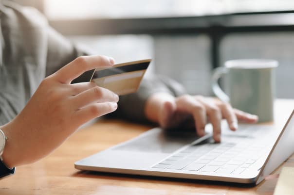 Hands holding credit card making online payment on laptop