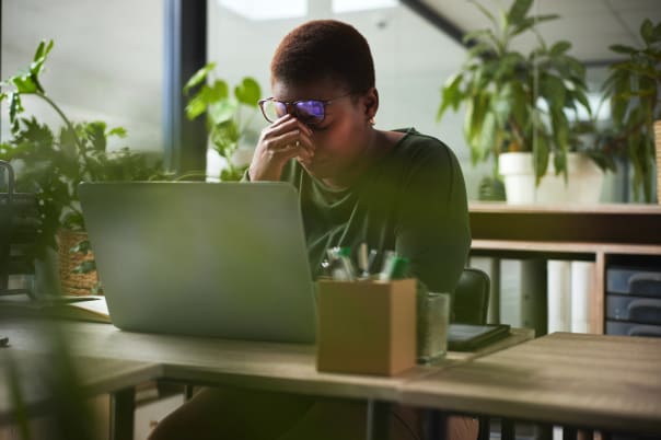 Woman at her laptop nursing a headache