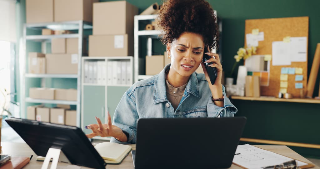 Frustrated woman at laptop on phone