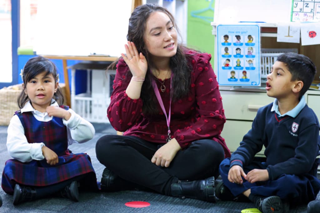 Teacher in classroom teaching two kids