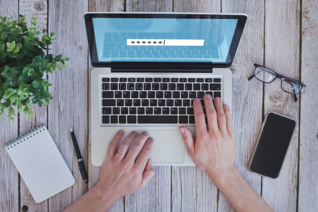 Hands entering password on laptop
