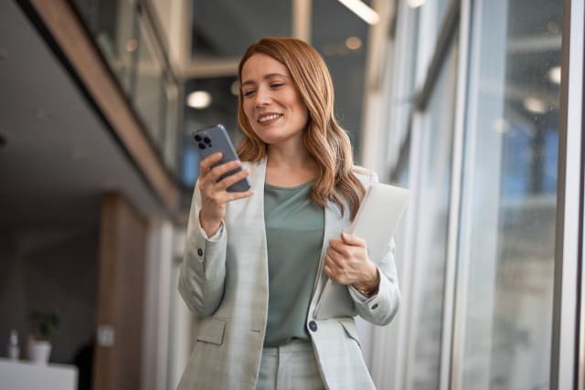 Professional woman looking at phone in office lobby