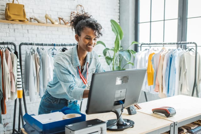 Woman working at POS system at retail clothing store
