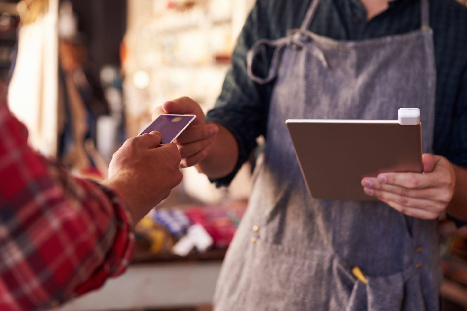 Man handing credit card to woman holding an iPad point of sale device