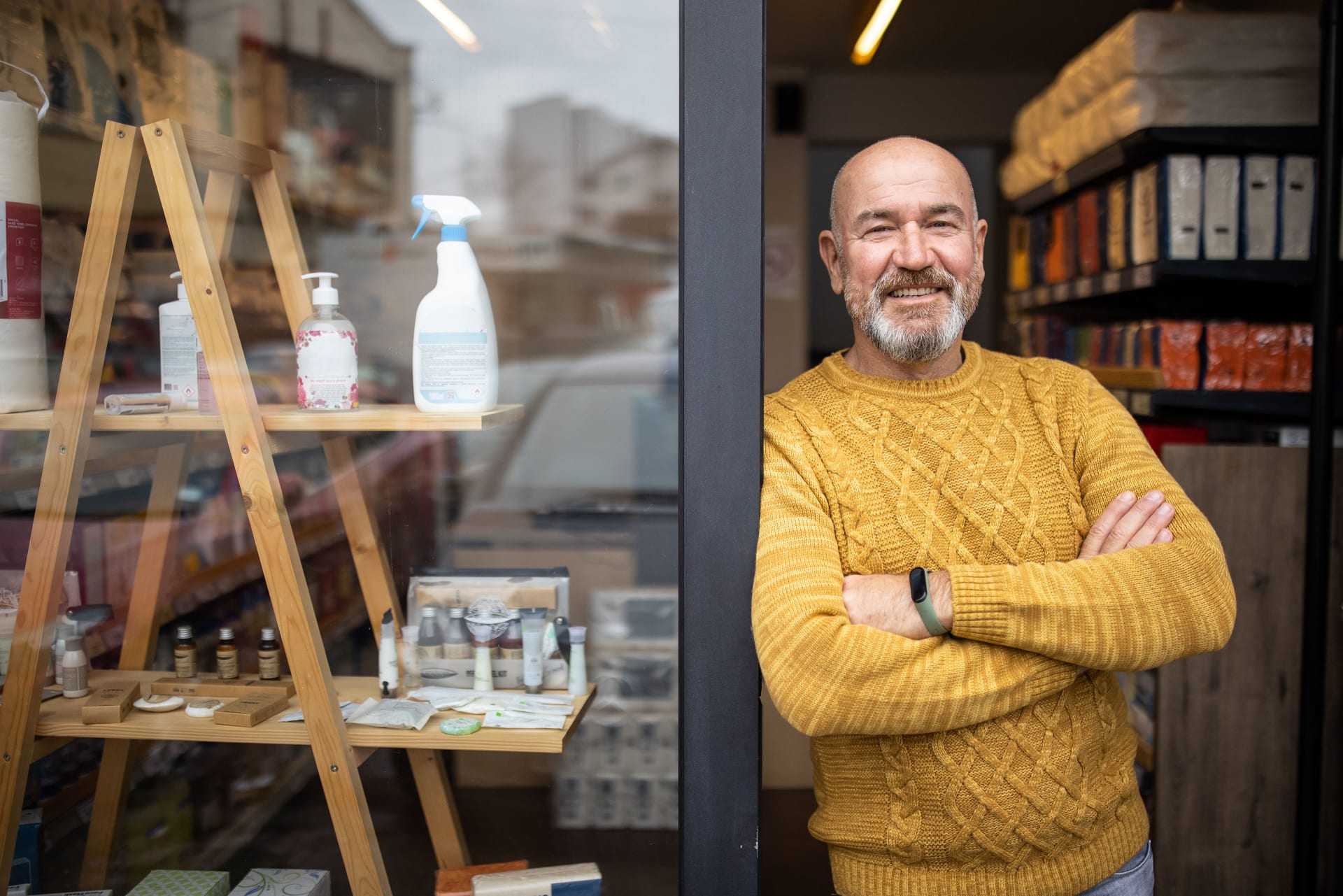 Man with arms crossed standing next to store window