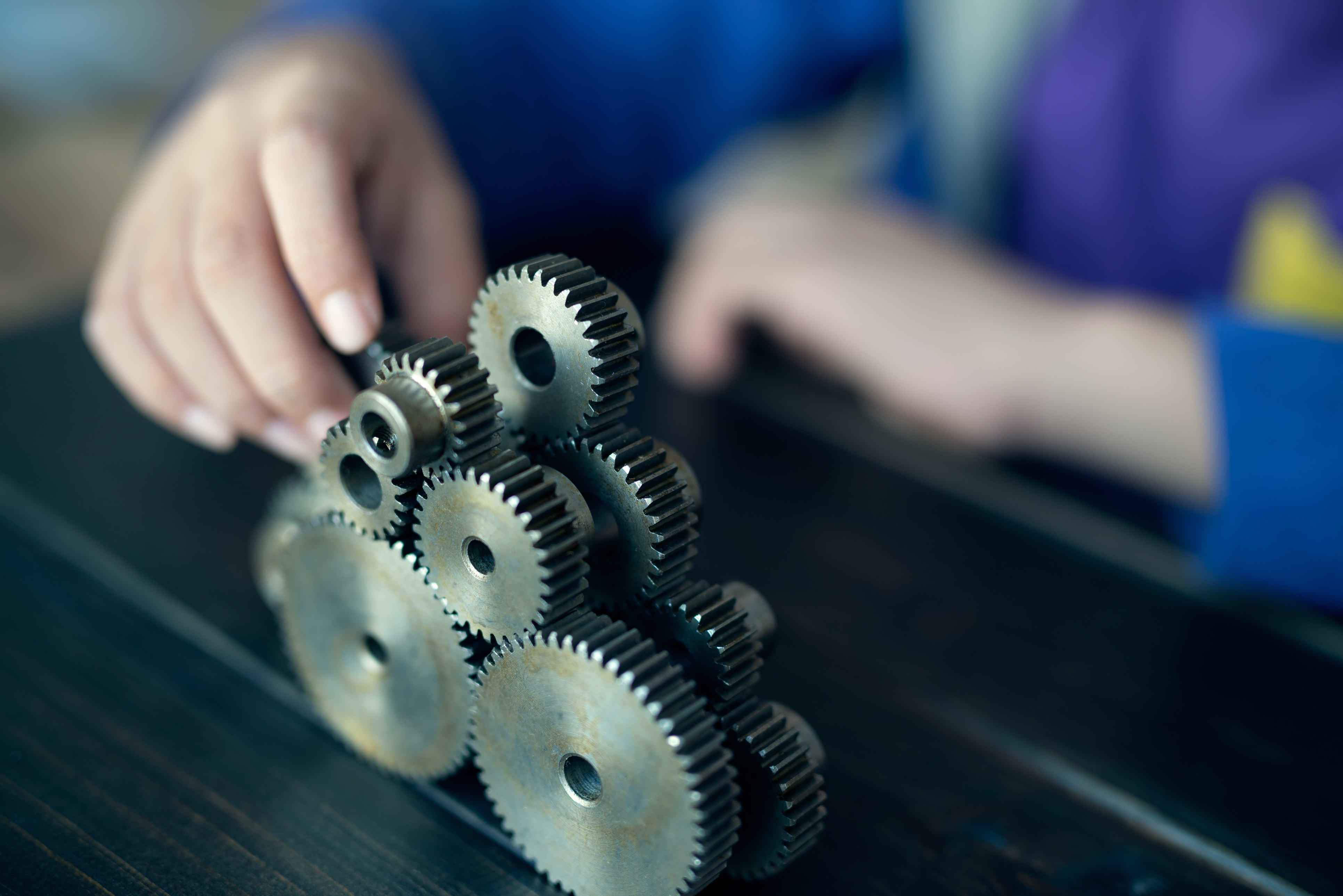 Hands connecting metal cogs together