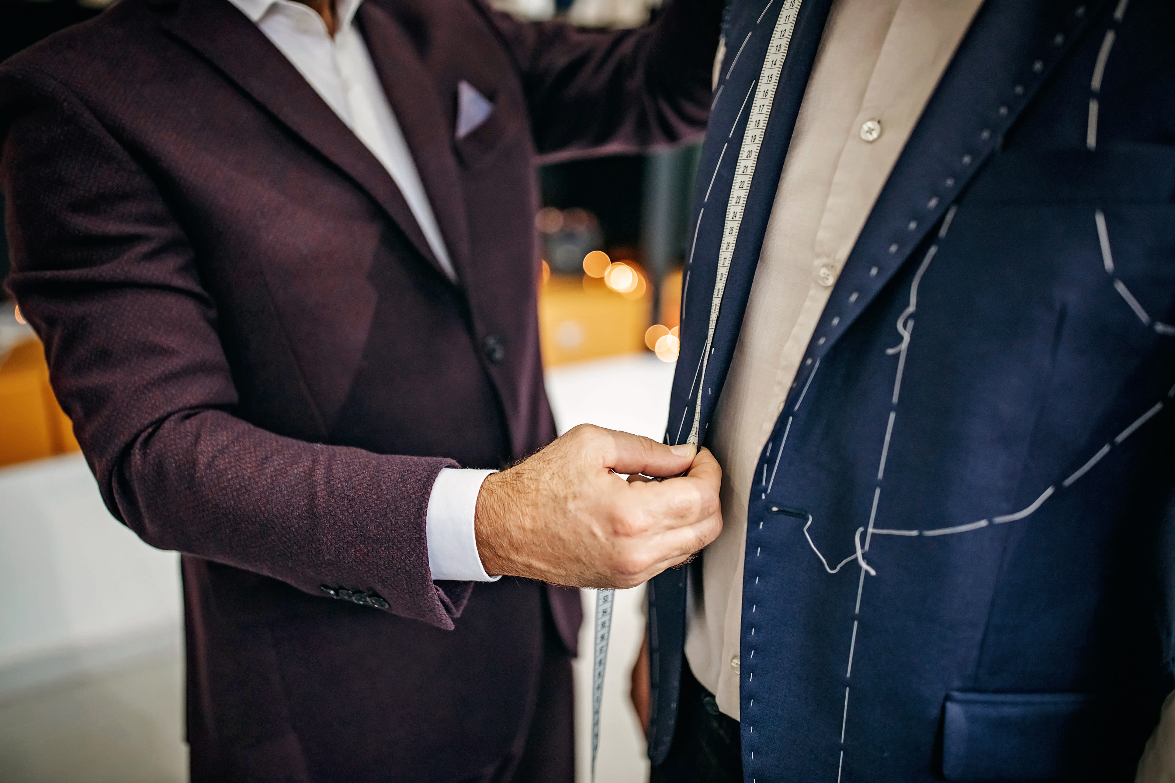 Close up on tailor's hands adjusting bespoke jacket