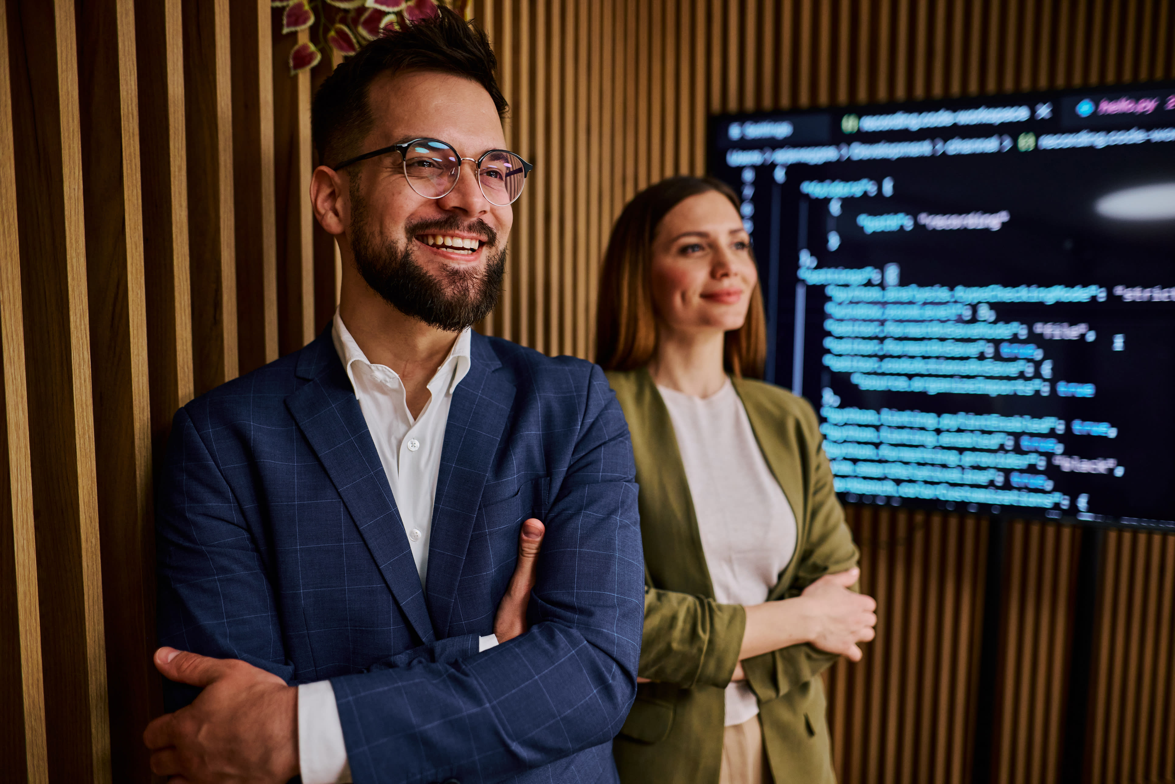 Two happy professionals in front of screen full of computer code