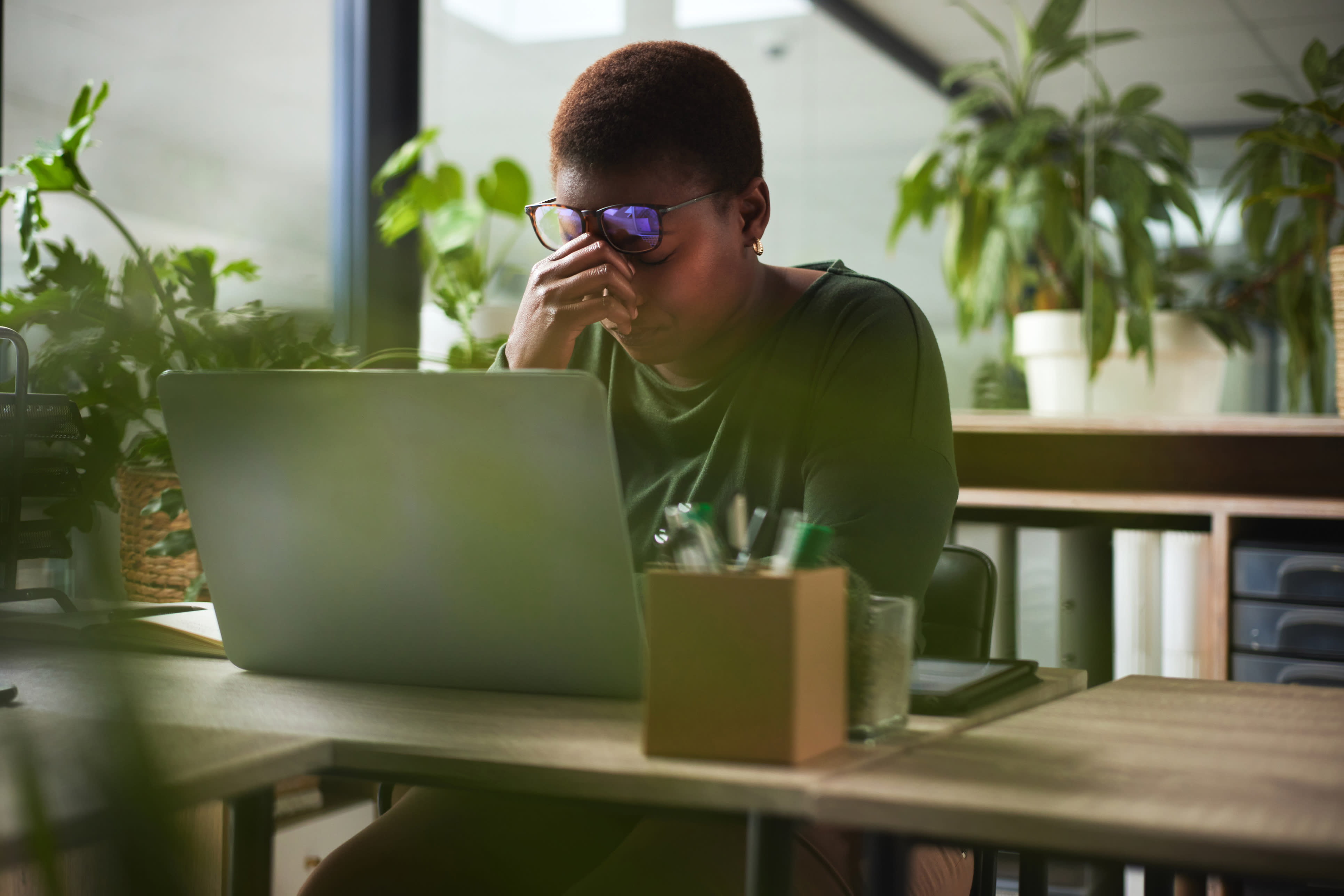 Woman at her laptop nursing a headache