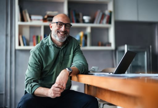 Professional man smiling at desk in front of laptop