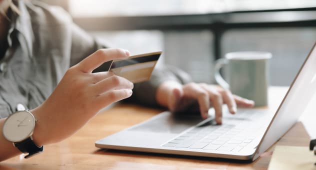 Hands holding credit card making online payment on laptop