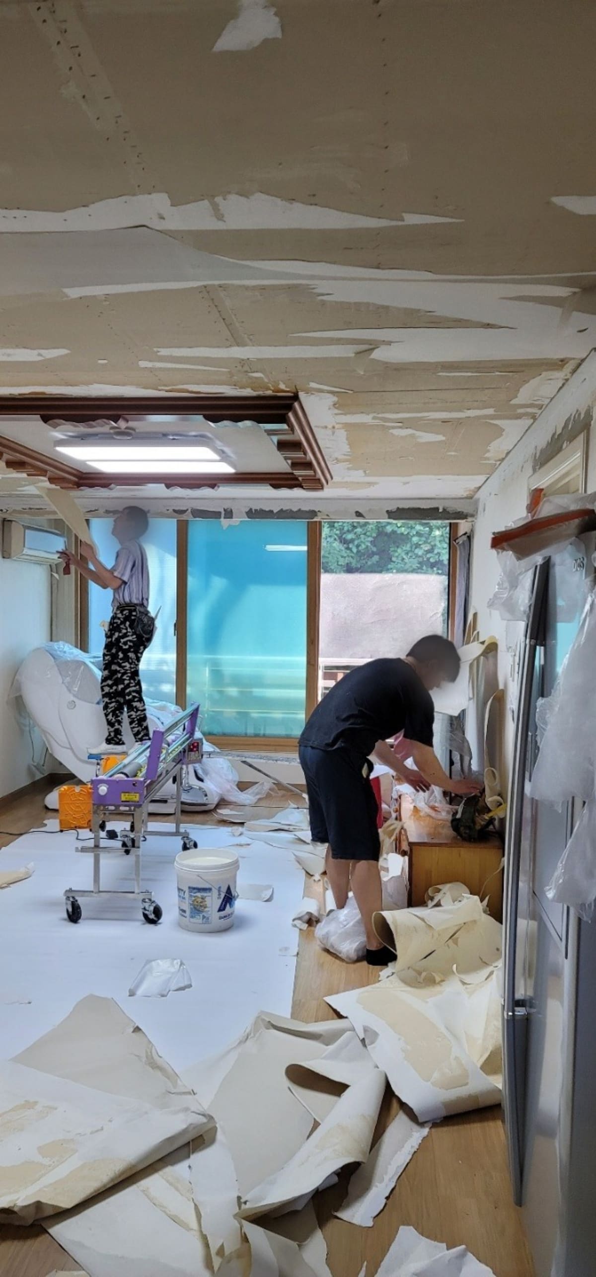 이동식 작업대에 올라 천장 구벽지를 걷어내는 2인 1조 작업