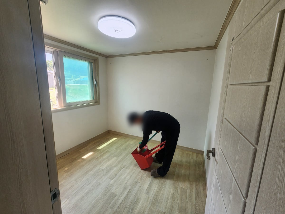 짐이 빠진 빈방 바닥을 빗자루와 쓰레받기로 마무리하는 모습