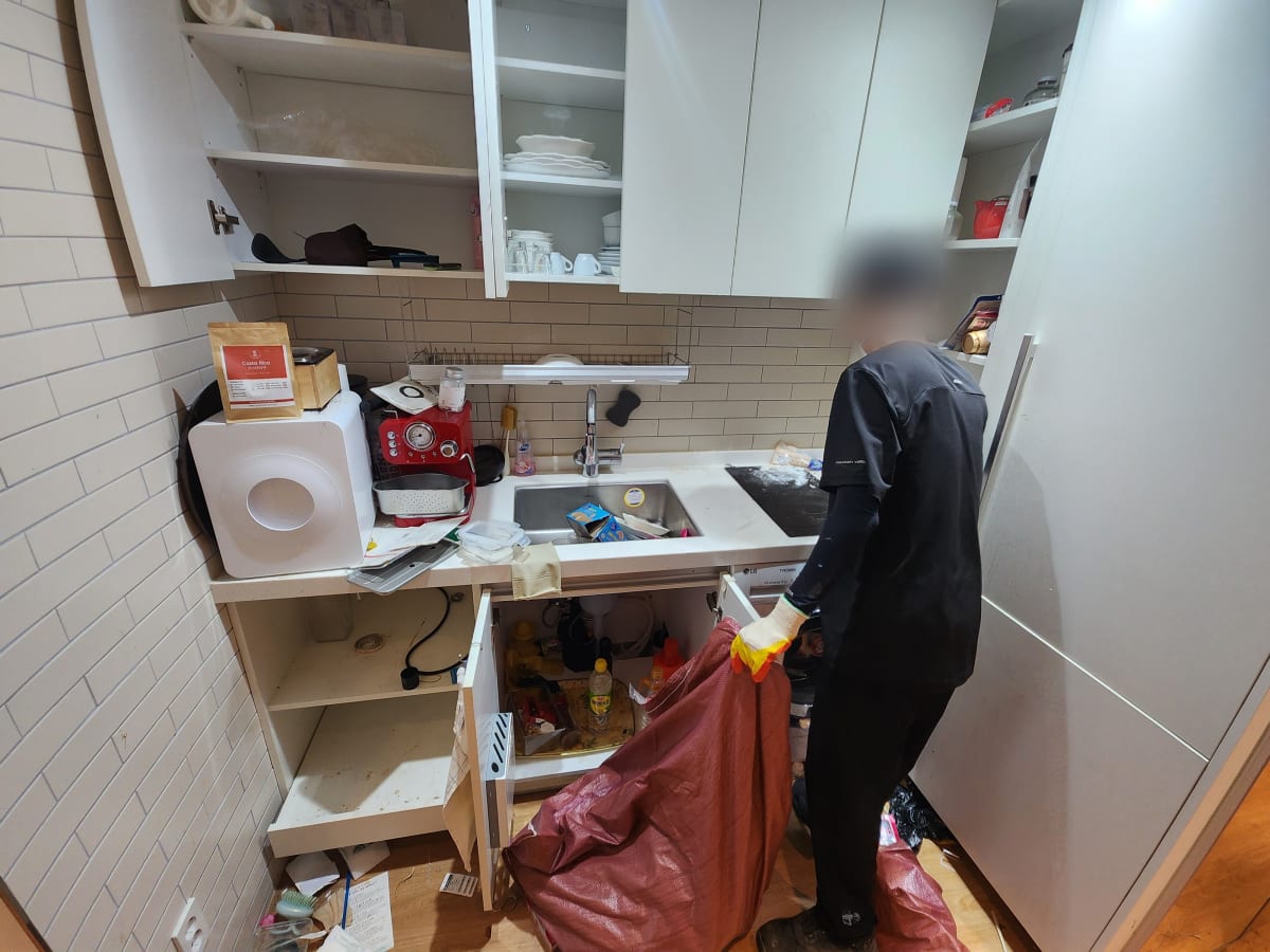 싱크대 하부장 세제와 잡화를 마대에 담는 작업