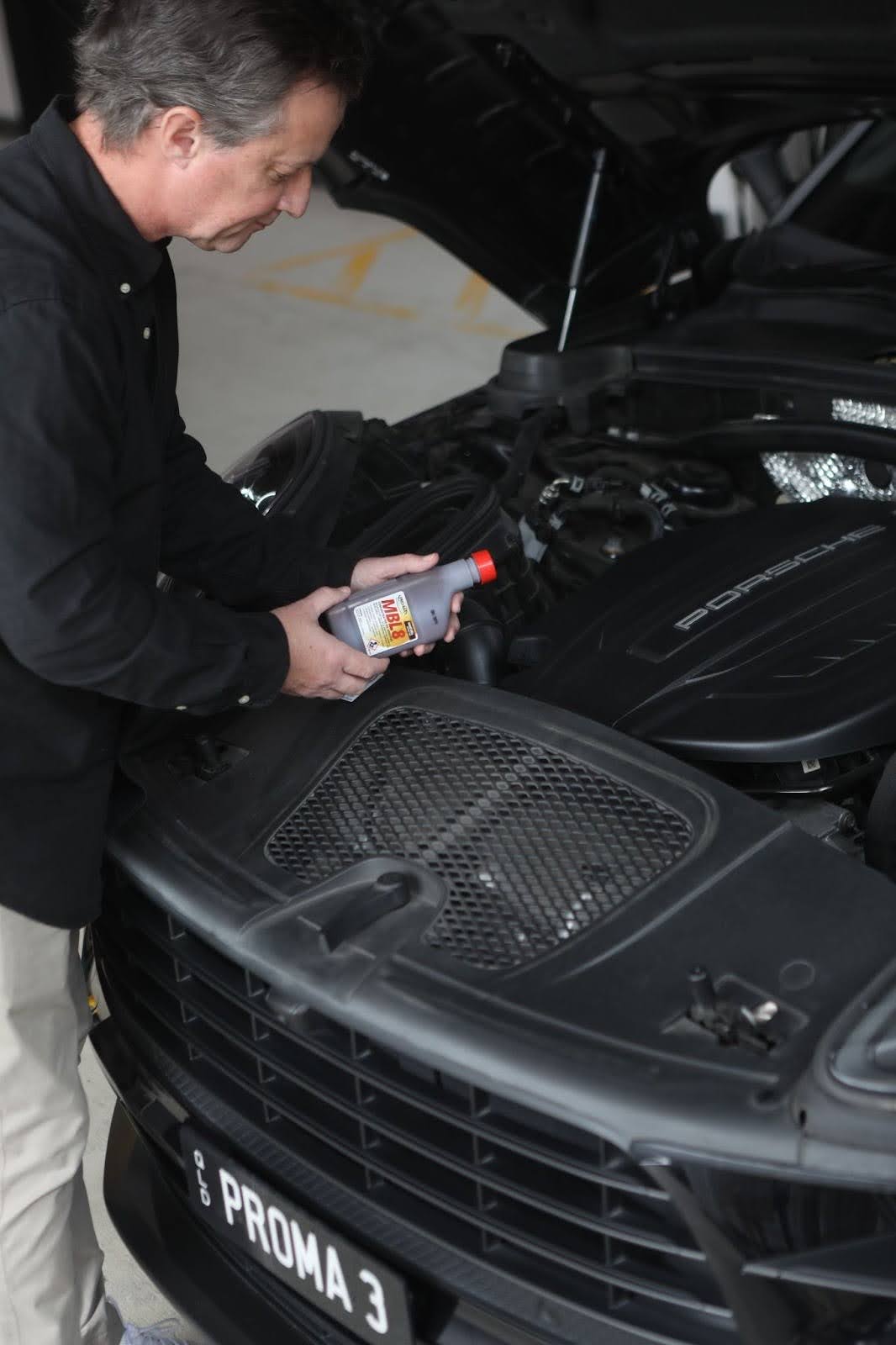 Man holding bottle of MBL8 in front of open car bonnet
