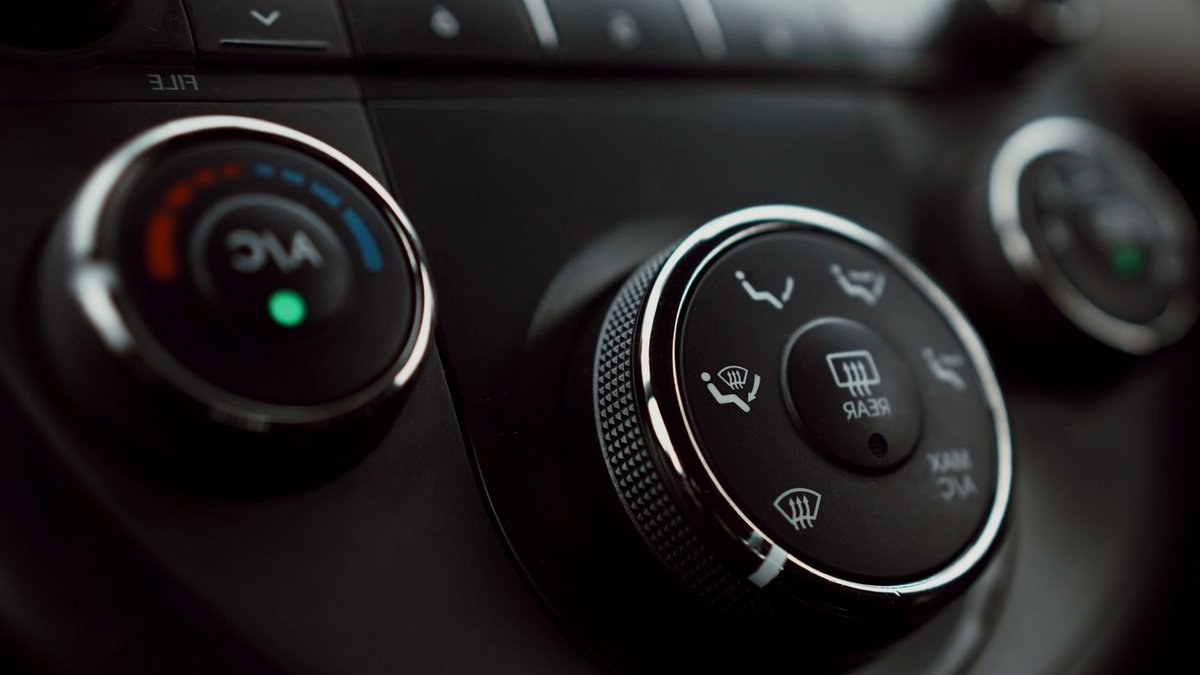 Detailed close-up of car dashboard air conditioning controls with focus on buttons and dials.