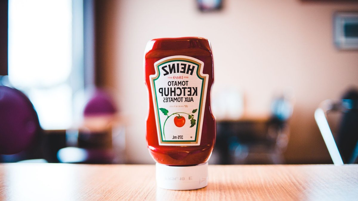 PerfectTed Co-Founder Marisa Poster Discusses Retail Trends A Heinz Tomato Ketchup bottle on a wooden table with blurred background indoors.