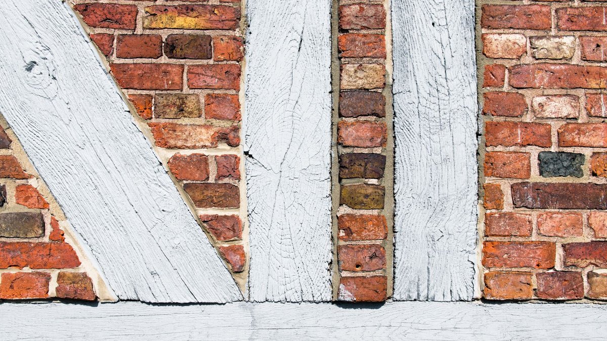 Timber Cladding Costs Rise: Budgeting for Wood Exteriors Close-up of a timber-framed red brick wall in Geesthacht, Germany showcasing old architecture.