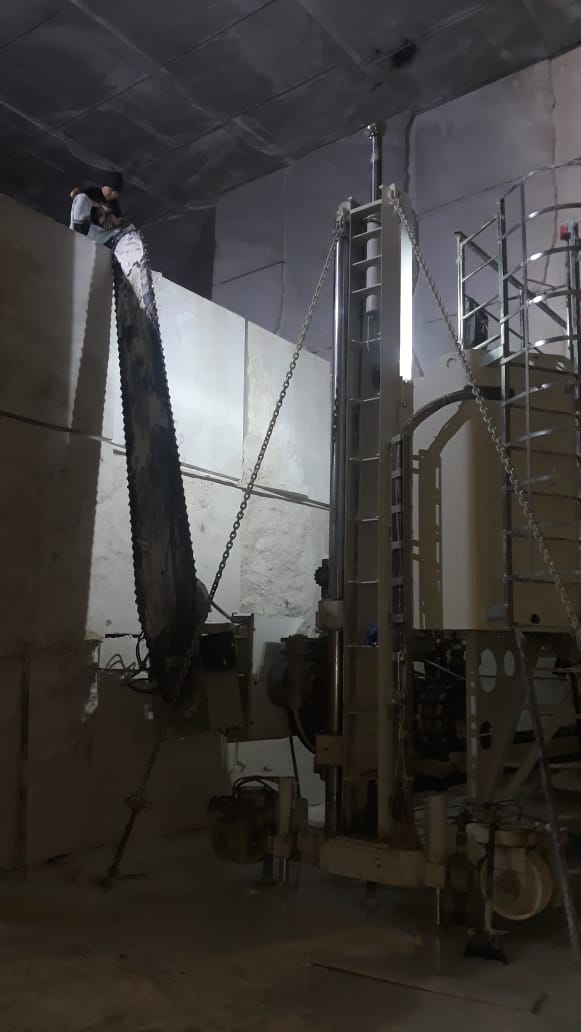 Arm saw cutting marble inside the underground quarry chamber