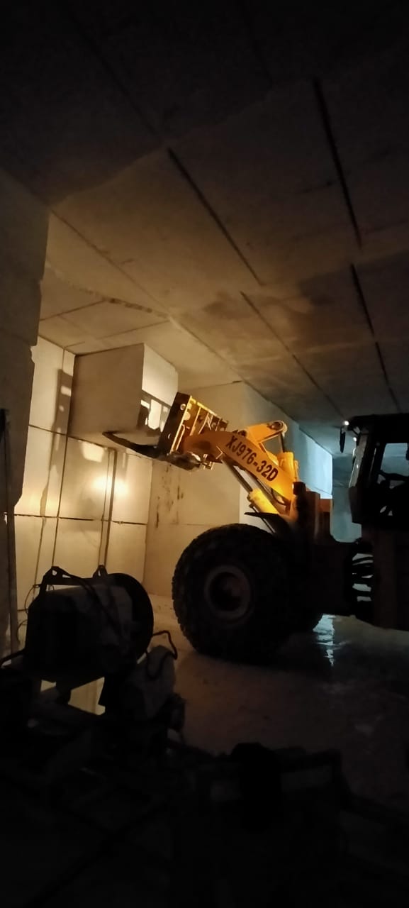 Yellow loader moving a marble block inside the underground quarry