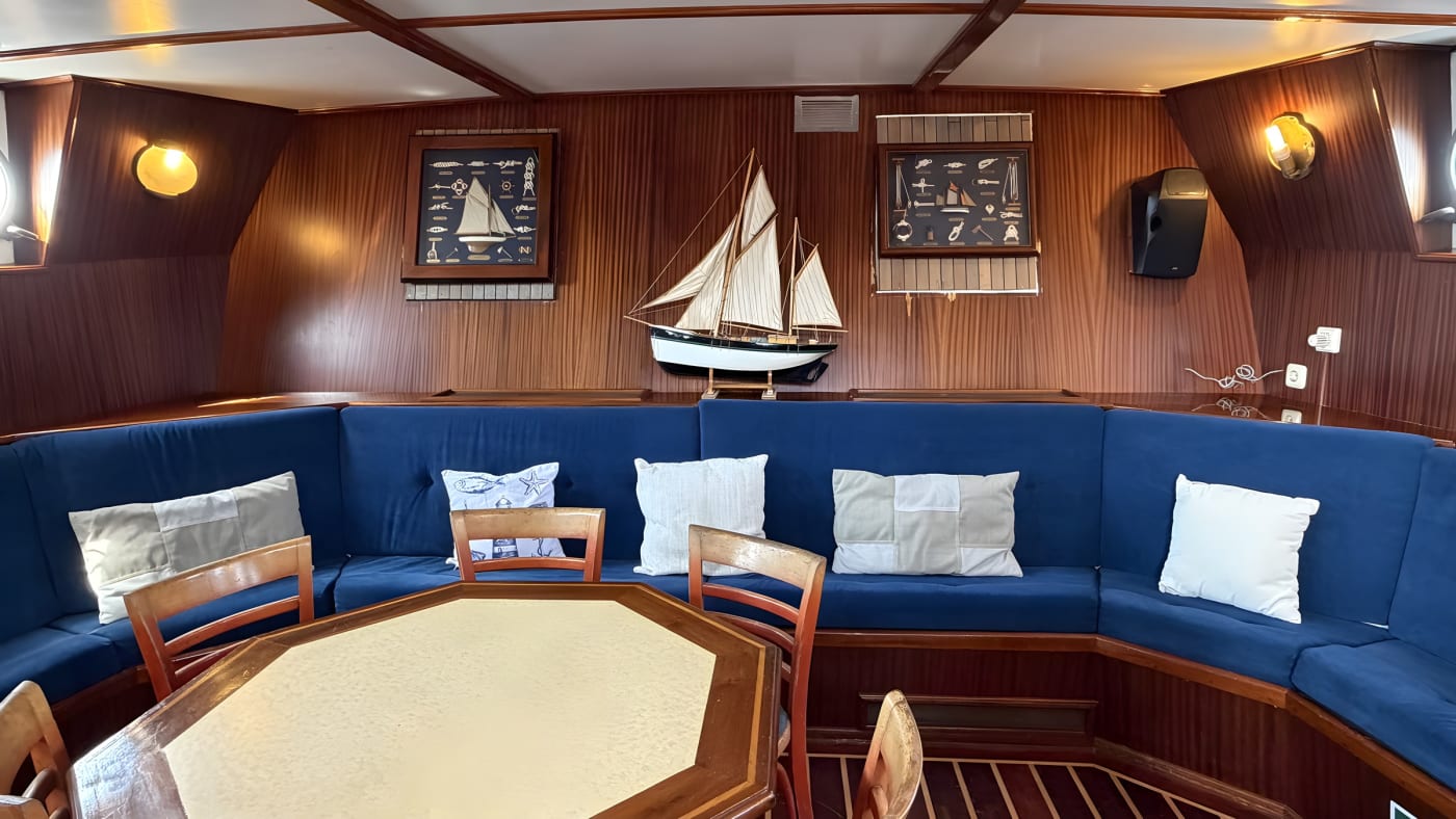 Le carré boisé d'un bateau, banquette bleue et maquette de goélette, lors d'une sortie en mer au large de Ramatuelle
