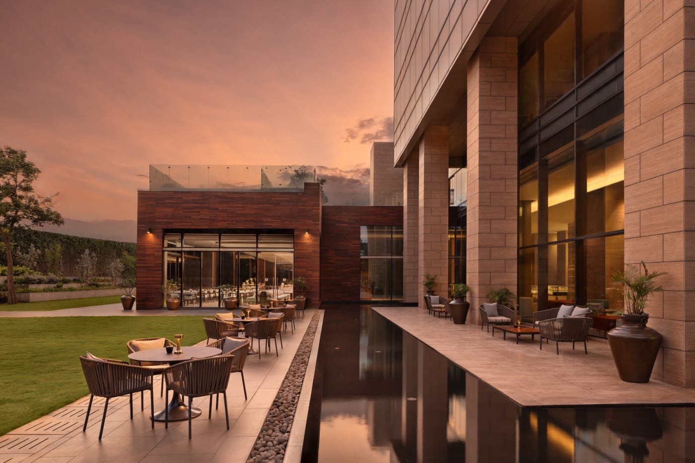 The Creek's terrace at sunset, between lawn and reflecting pool, at the foot of The Den Bengaluru, LXR Hotels & Resorts