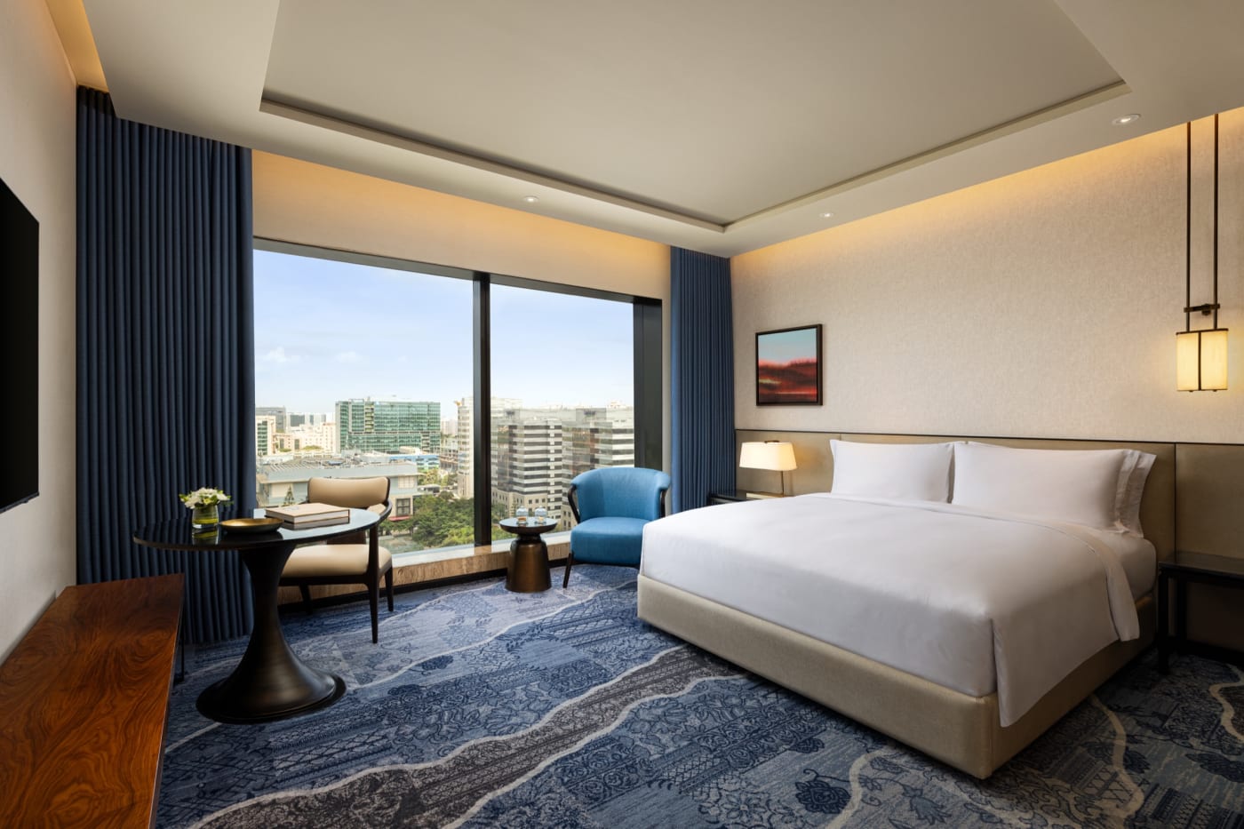 King Executive room at The Den Bengaluru, LXR Hotels & Resorts, with a blue rug, large bed and picture window over Whitefield