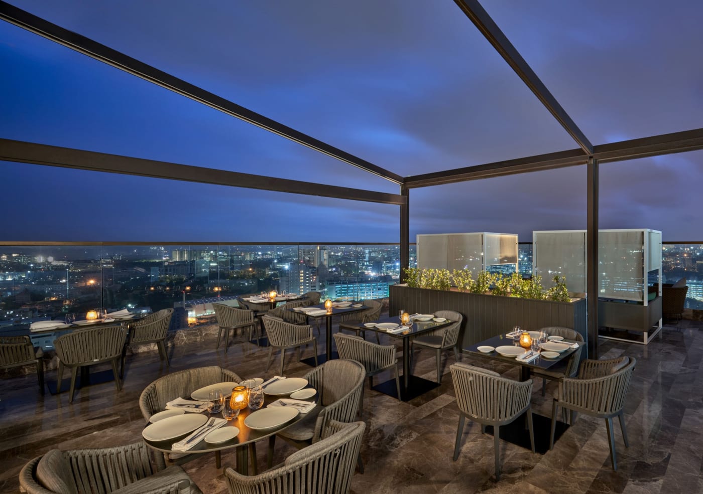 The terrace of the Layla rooftop restaurant at The Den Bengaluru, LXR Hotels & Resorts, at nightfall above the lights of Bengaluru