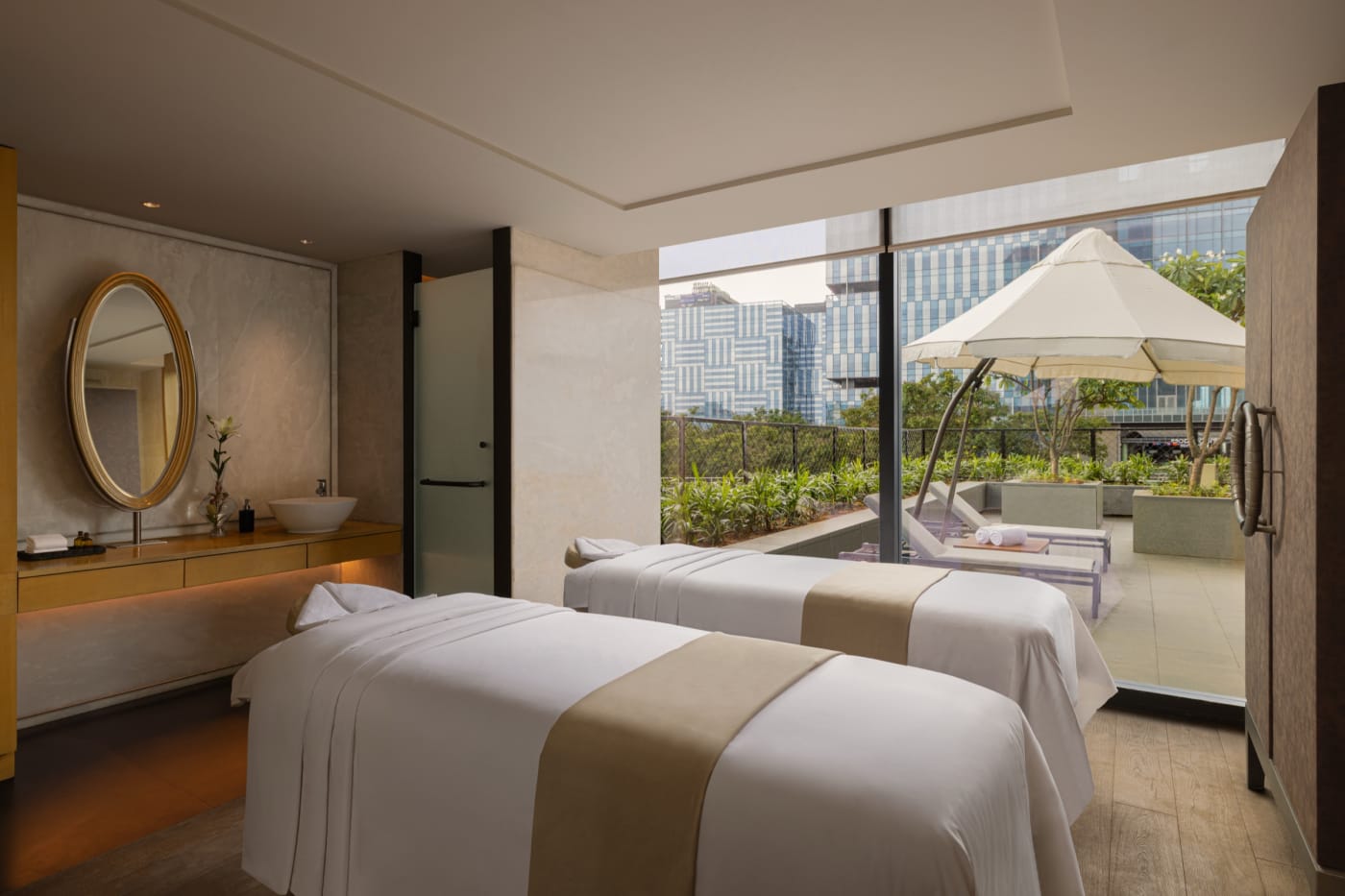 Couples' treatment room at The Sanctuary spa, The Den Bengaluru, LXR Hotels & Resorts, opening onto a planted terrace