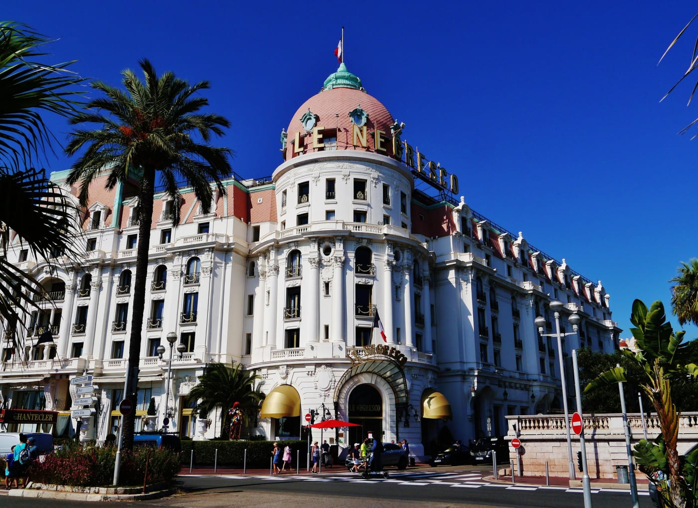 Le Negresco et sa coupole rose sur la promenade des Anglais à Nice, entre les palmiers