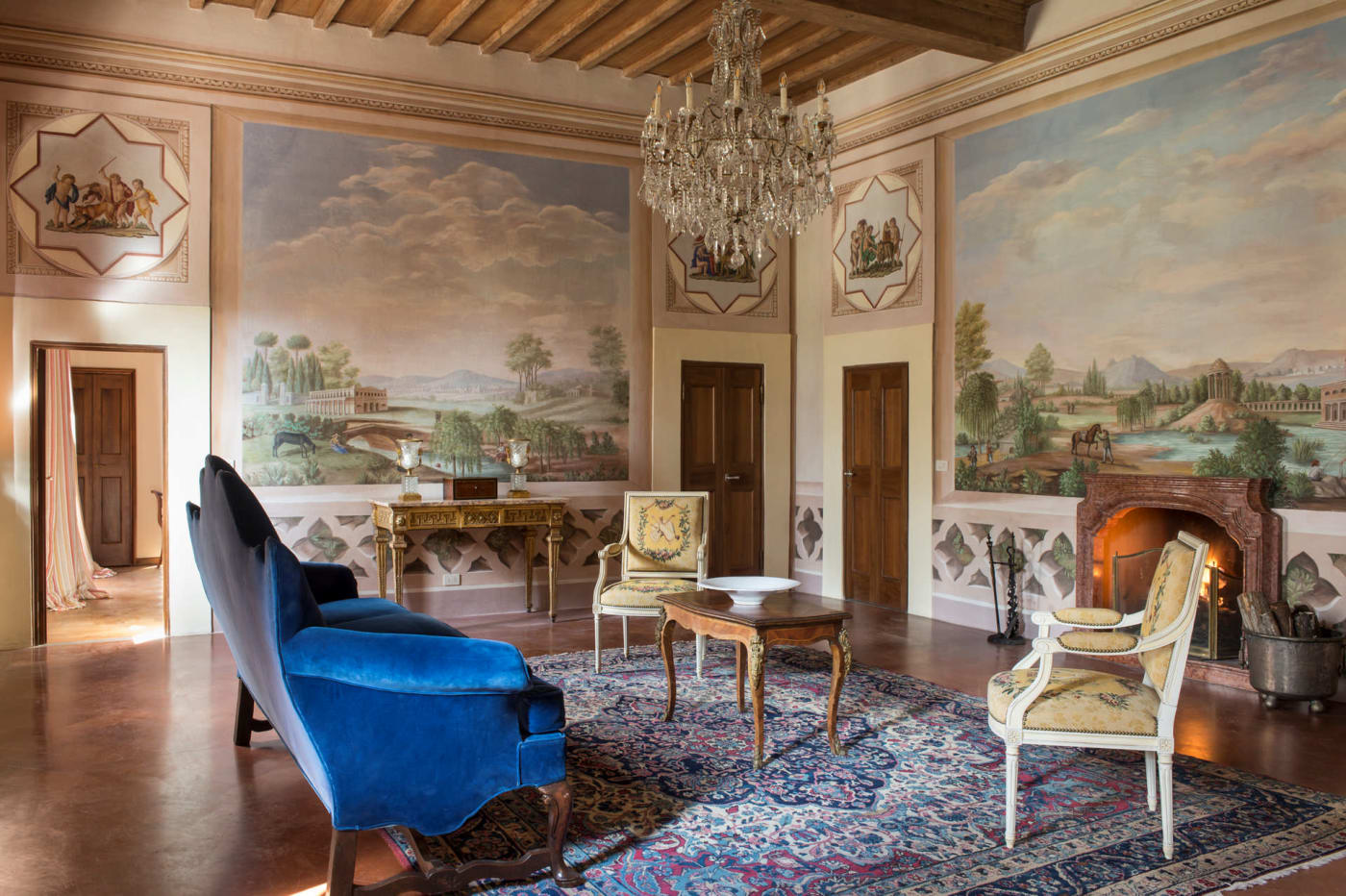Salão com paredes pintadas com paisagens e lareira da Villa Viesca, propriedade Viesca Toscana